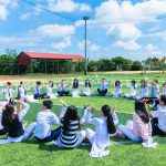 a group of international primary school students in Malaysia lifting hands up at a field