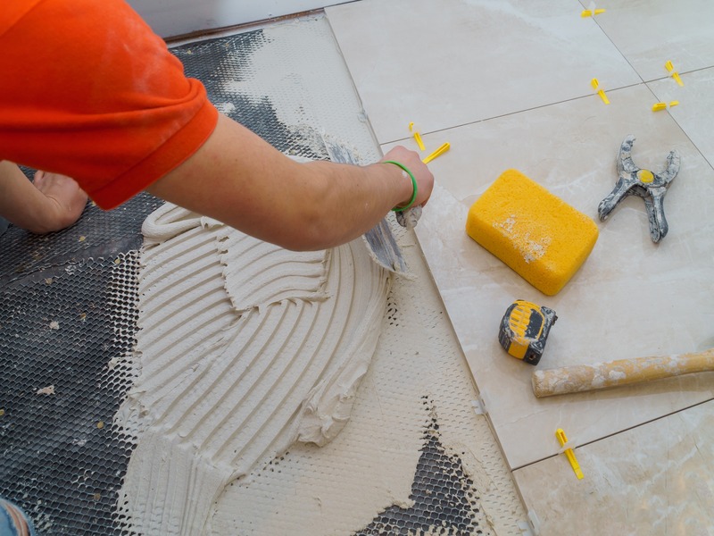 A homeowner carefully laying new bathroom floor tiles to create a modern and stylish design.