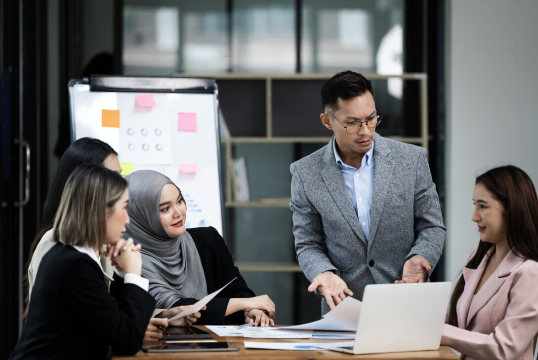 A corporate training session is actively attended by a diverse group of Malaysian professionals under the direction of an instructor.