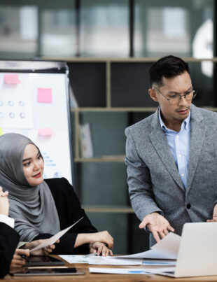 A corporate training session is actively attended by a diverse group of Malaysian professionals under the direction of an instructor.